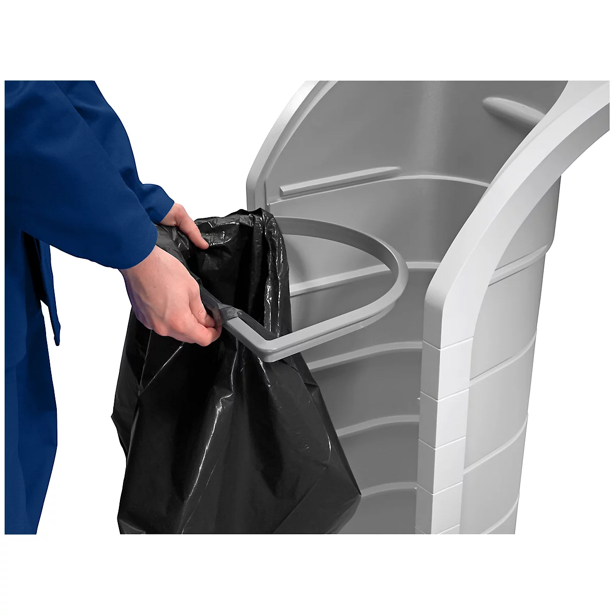 Person puts a black garbage bag into a gray trash can. The bin has a gray handle.