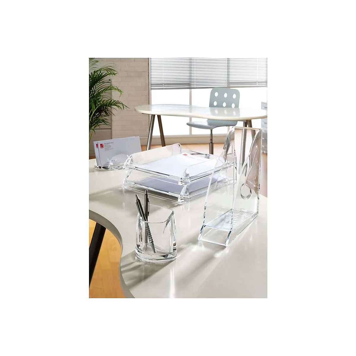 Ensemble d'organisation de bureau en plastique transparent sur un bureau. Comprend des corbeilles à papier, un porte-stylo et un bac à lettres.