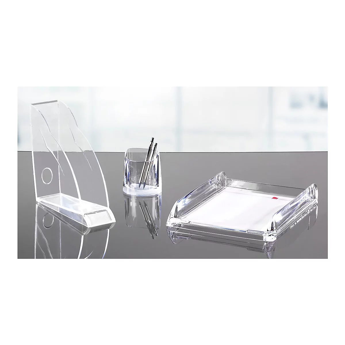 Accessoires de bureau en plastique transparent : trieurs de papier, porte-stylo, bac à courrier sur une surface brillante.