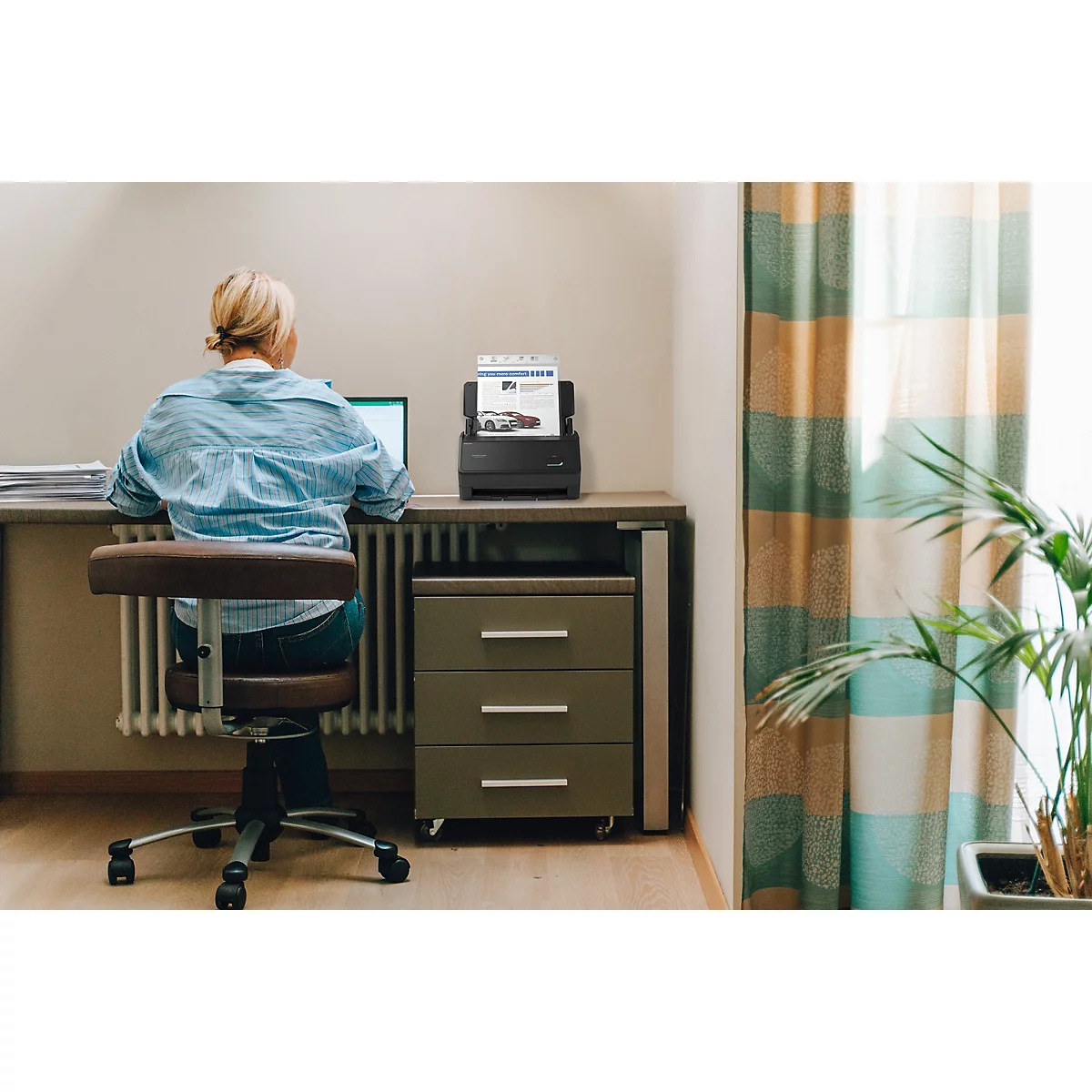 Eine Frau arbeitet im Homeoffice an einem Schreibtisch mit einem Dokumentenscanner.