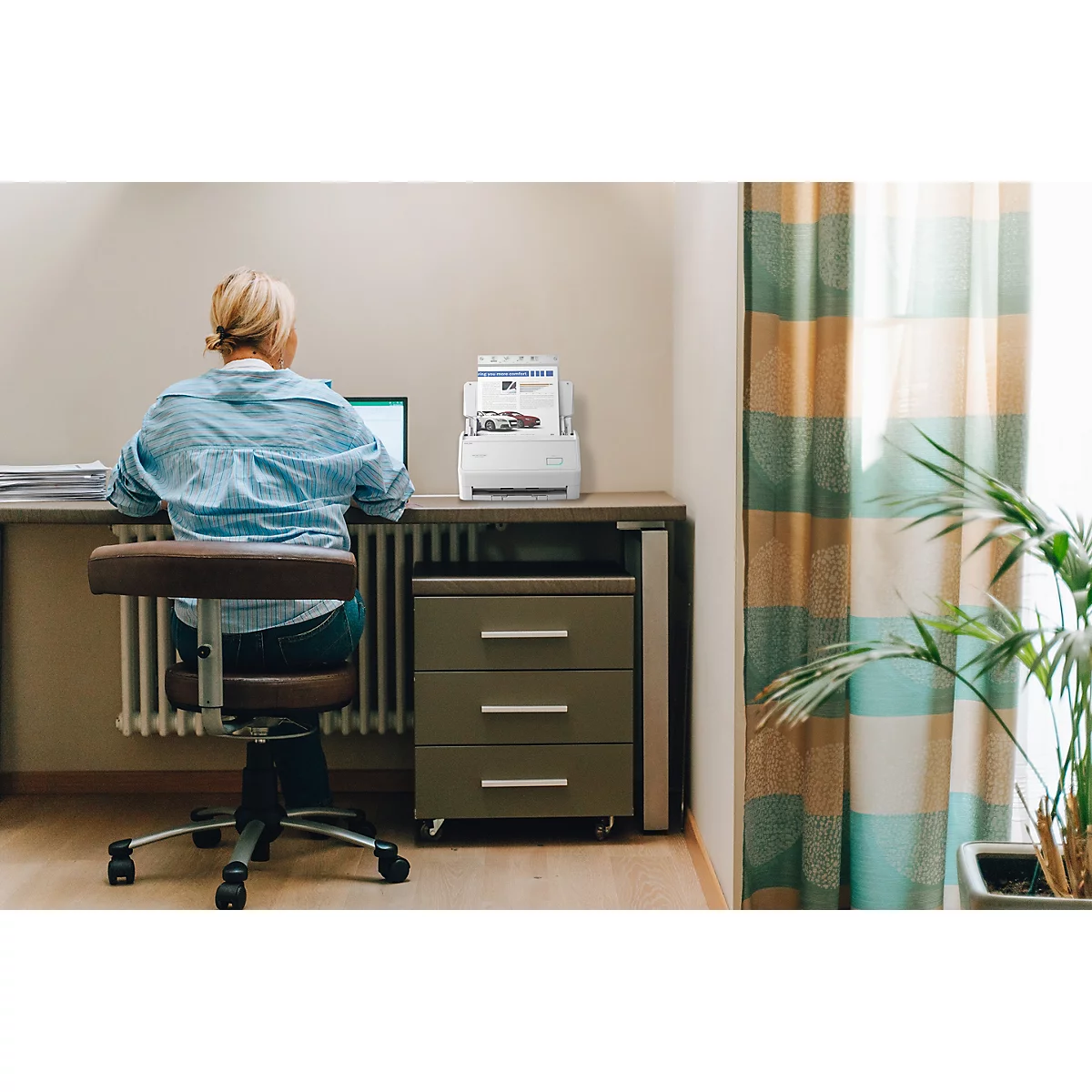Eine Frau arbeitet an einem Schreibtisch mit Laptop und einem Dokumentenscanner im Homeoffice.