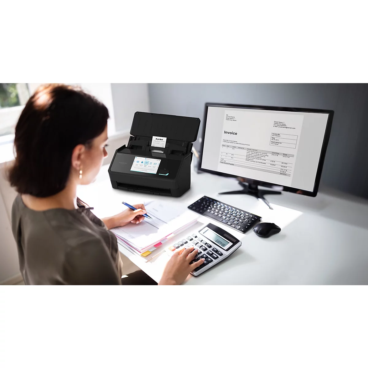 Eine Frau arbeitet an einem Schreibtisch mit einem Dokumentenscanner, Taschenrechner und Computer.