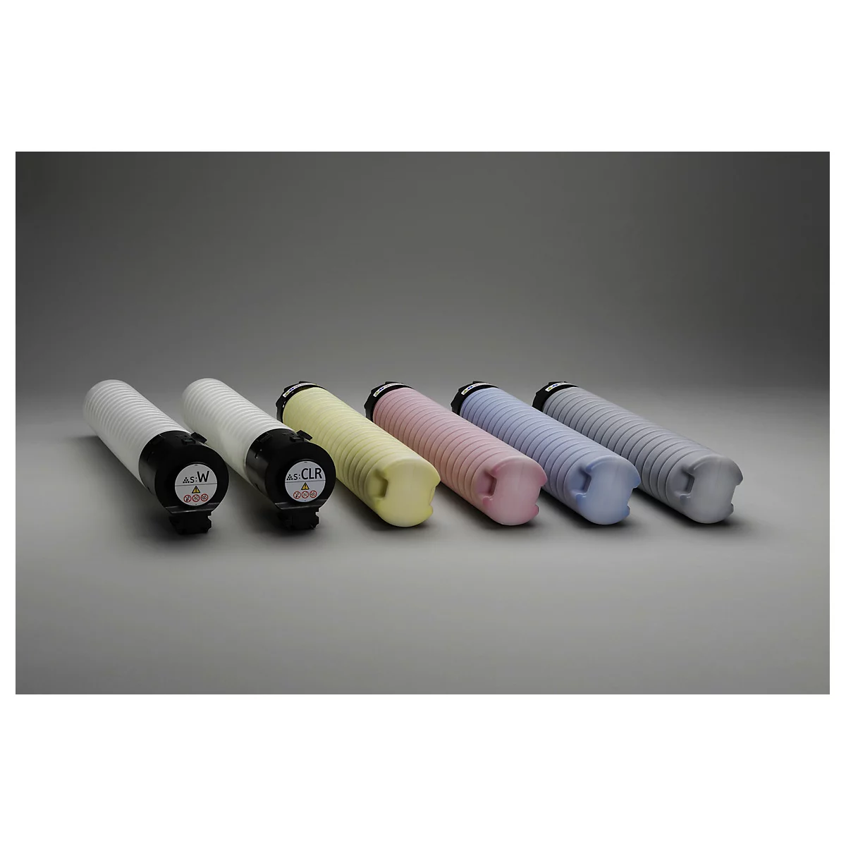 Sechs zylinderförmige Tonerkartuschen in verschiedenen Farben. Die Kartuschen liegen nebeneinander. Links weiß, dann gelb, rosa, hellblau und grau.