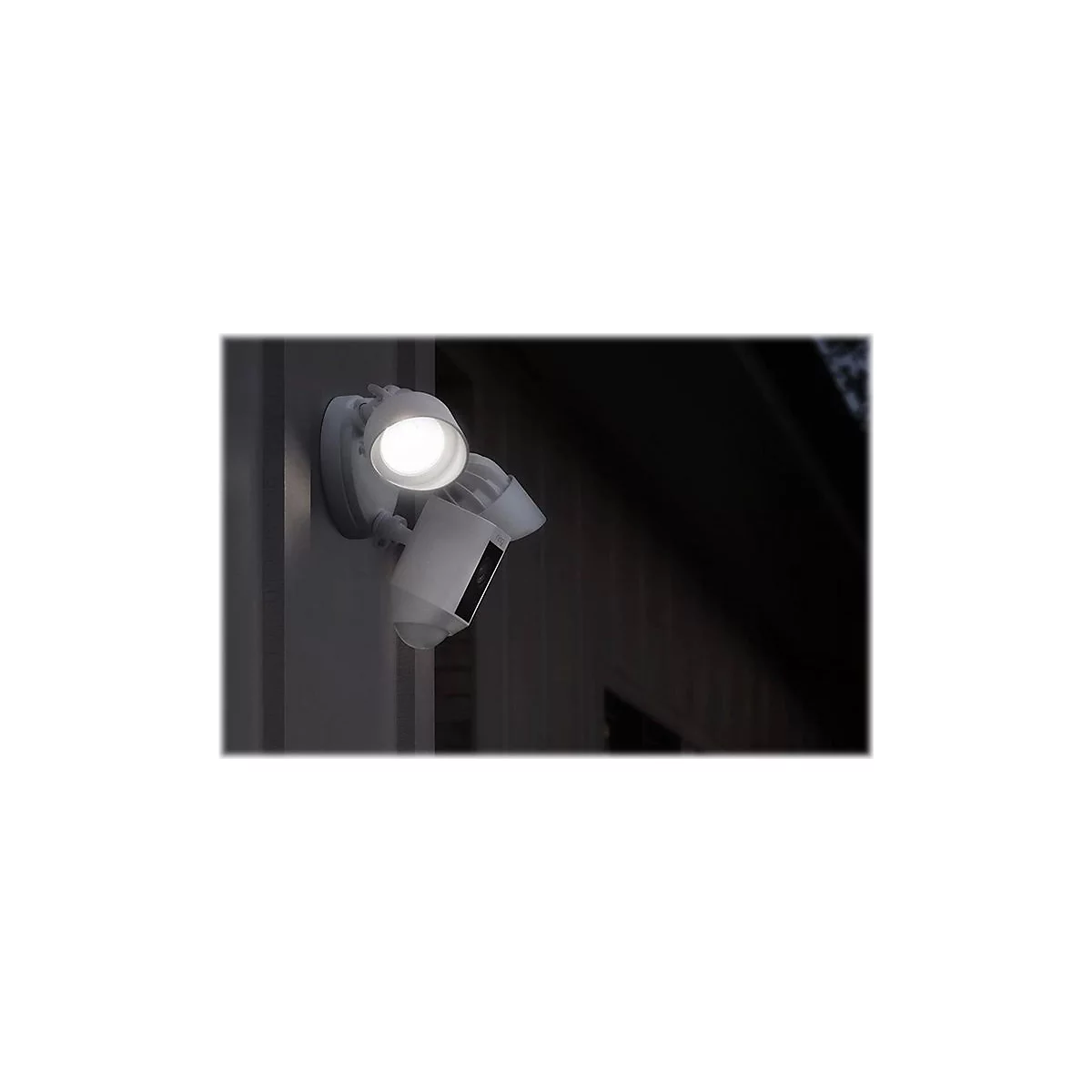 Eine weiße Außenleuchte ist an einer Wand montiert. Die Lampe leuchtet hell. Ein dunkler Hintergrund.