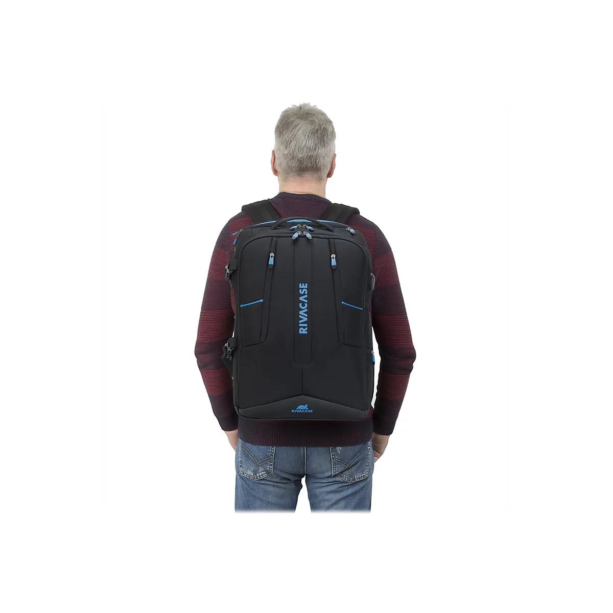 Ein Mann mit grauem Haar trÃ¤gt einen schwarzen Rucksack. Auf dem Rucksack ist das Wort RIVACASE in blau geschrieben.