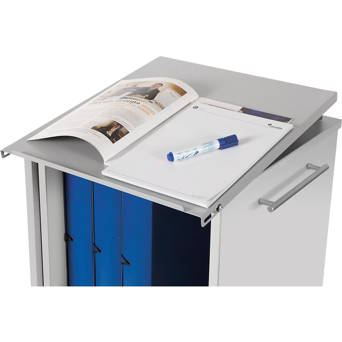 Armoire de bureau grise, couvercle avec bloc-notes, magazine et stylo. Tiroirs avec des dossiers bleus.