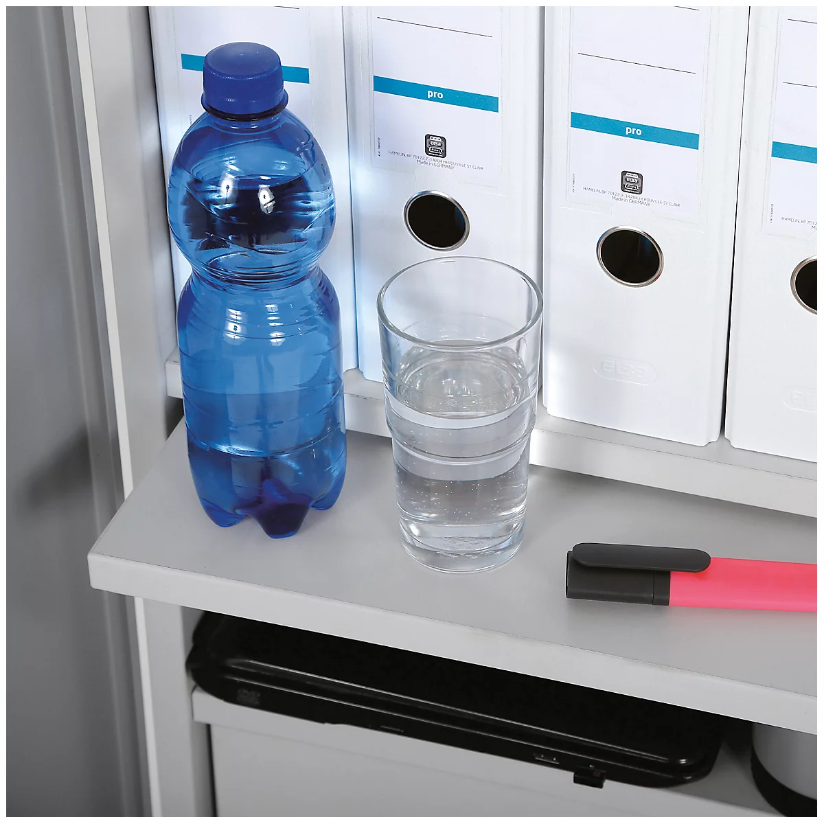 Blue water bottle and glass of water next to file folders on a shelf.