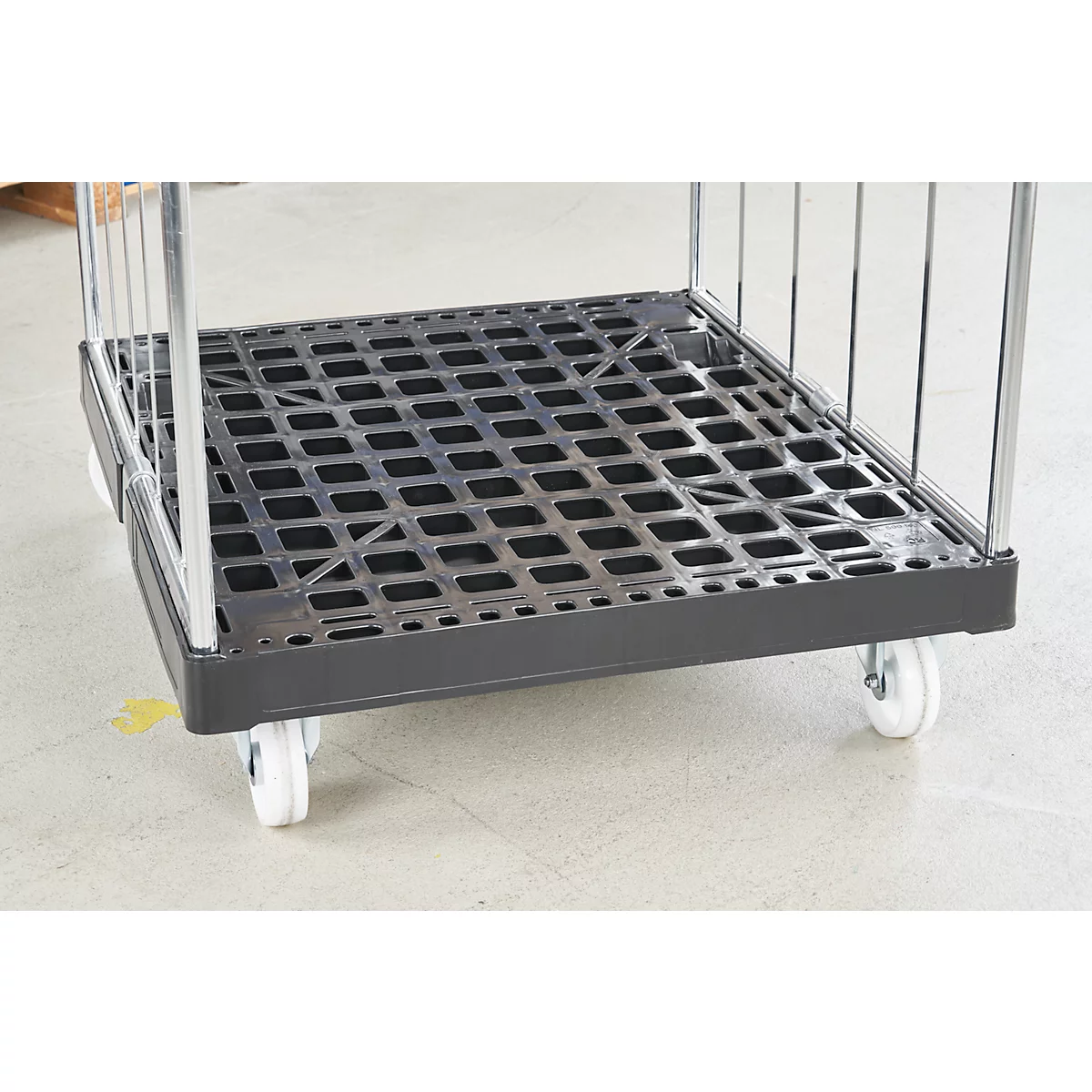 Zwarte rolcontainer met metalen frame en kunststof vloer. Wielen onderaan, leeg.