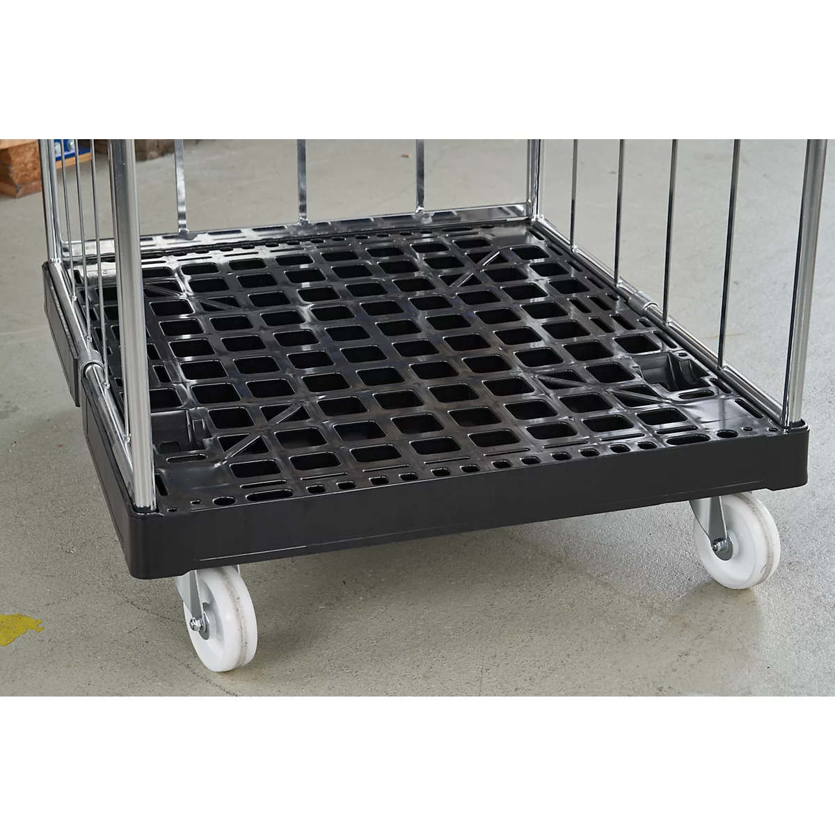 Zwarte rolwagen met roosterstructuur, op witte wielen, grijze achtergrond.