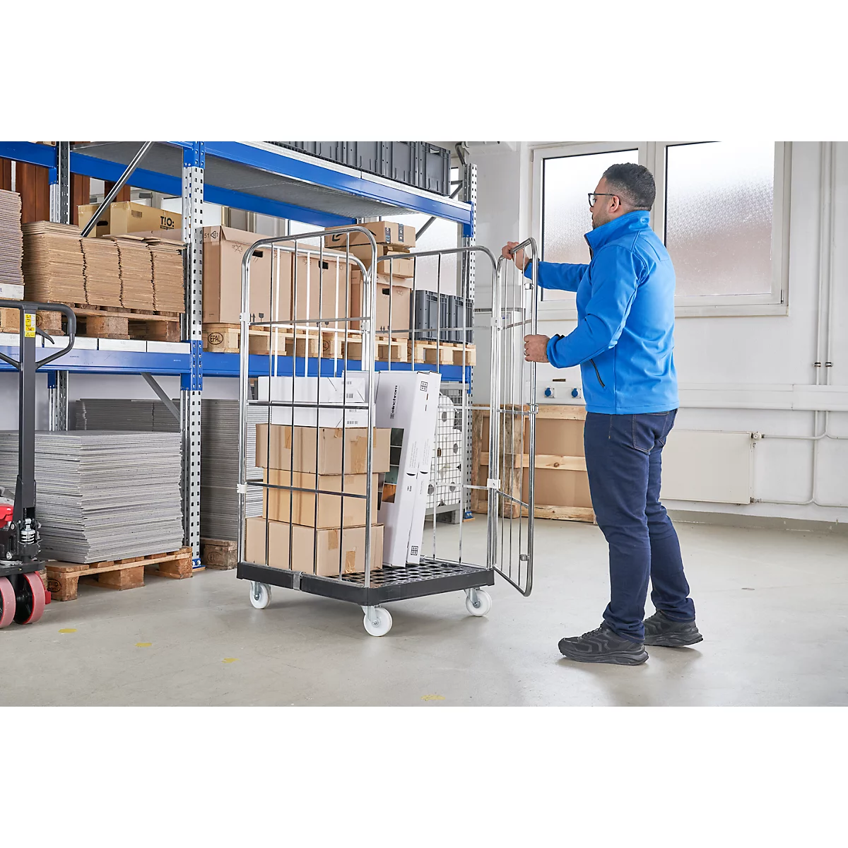 Man duwt rolkooi met dozen in een magazijn. Meer dozen op planken op de achtergrond.