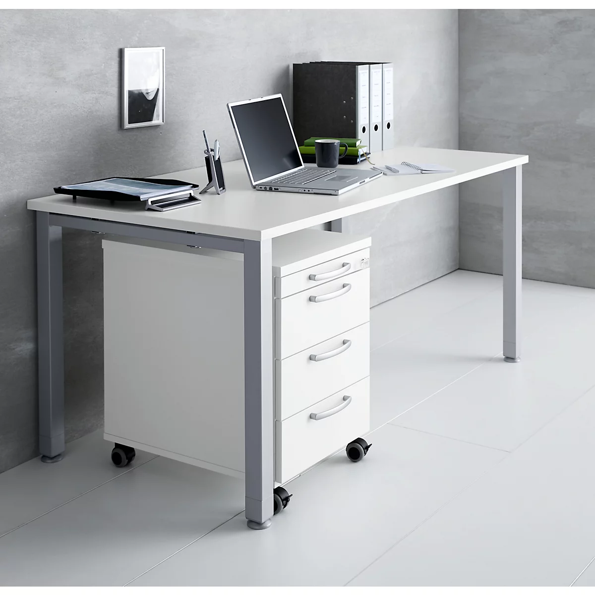 White desk with drawers, laptop, folders, and pen holder against a grey background.