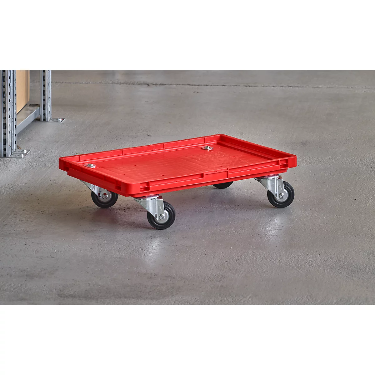 Carro de transporte rojo con cuatro ruedas sobre suelo gris.