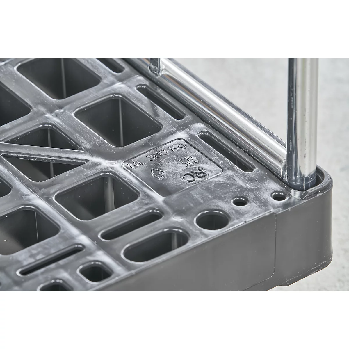 Gros plan d'une étagère en plastique noir avec des trous et un poteau métallique.