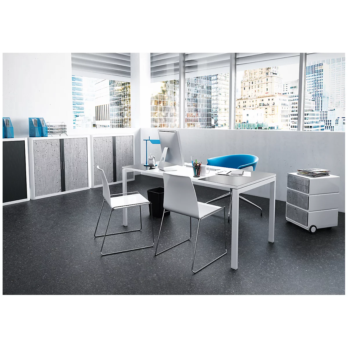 A modern office with a desk, chairs, and a view of a city. Windows with blinds, blue chair, grey cabinets and dark floor.