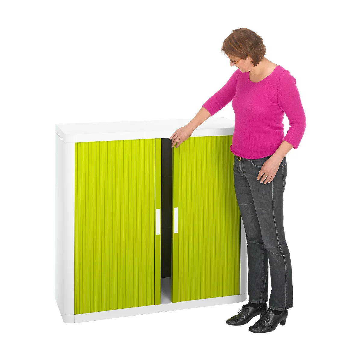 A woman opening a cabinet door. The cabinet is white with bright green doors. The woman is wearing a pink top and jeans.