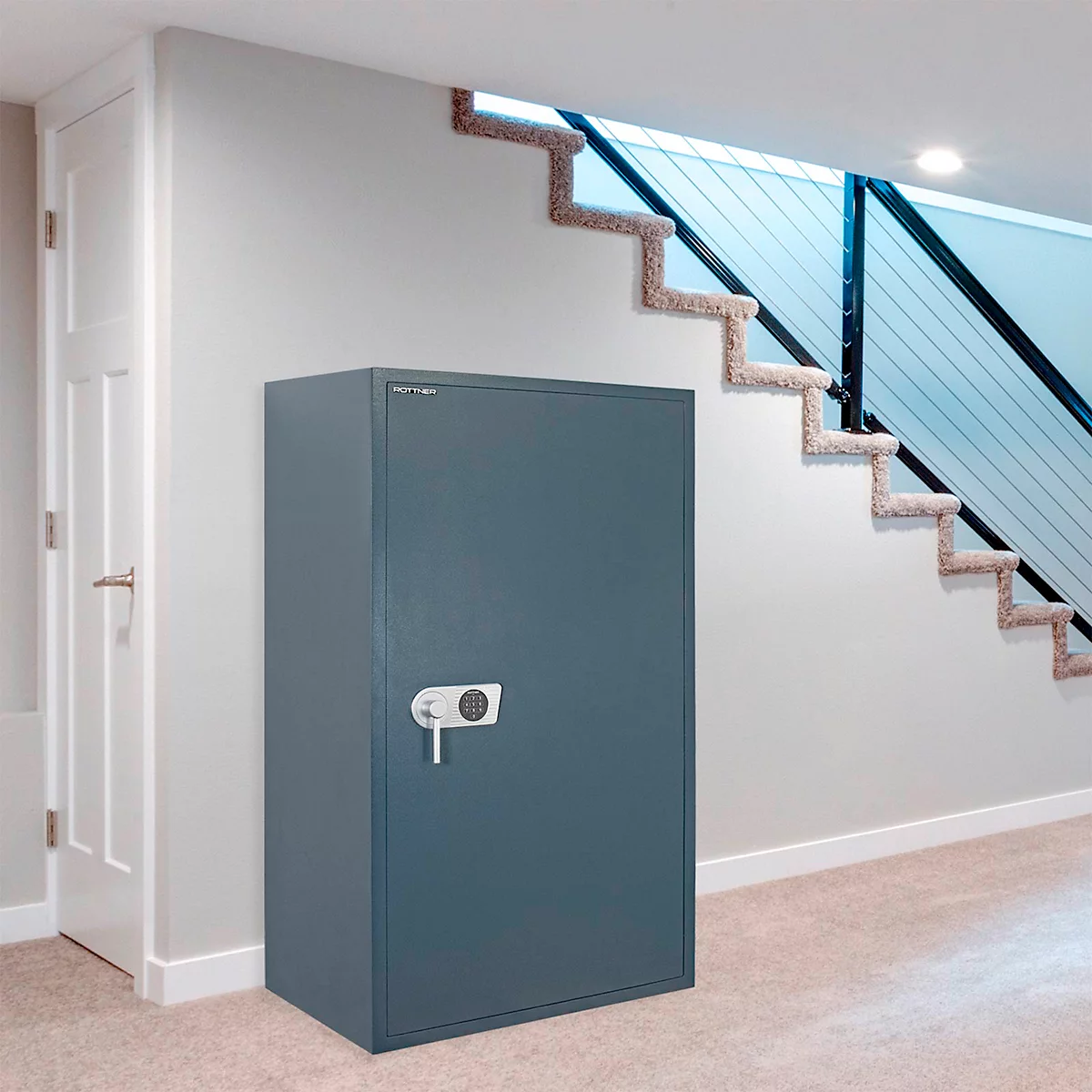 Coffre-fort bleu-gris avec serrure numérique dans une pièce lumineuse à côté d'un escalier.