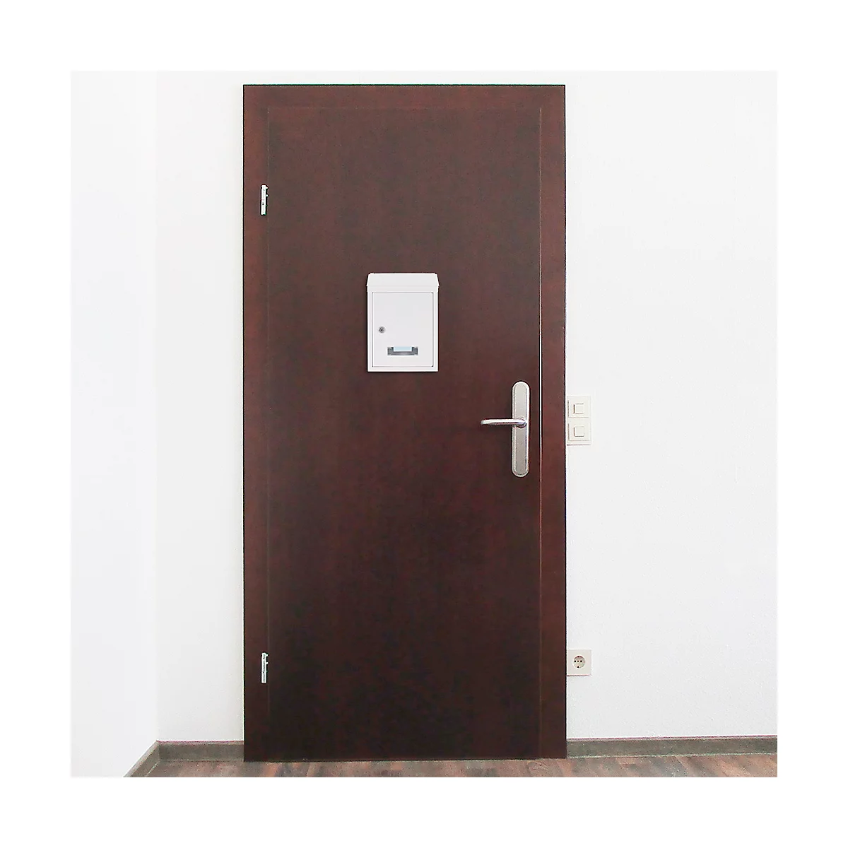Porte brun foncé avec boîte aux lettres, poignée de porte et mur blanc en arrière-plan.
