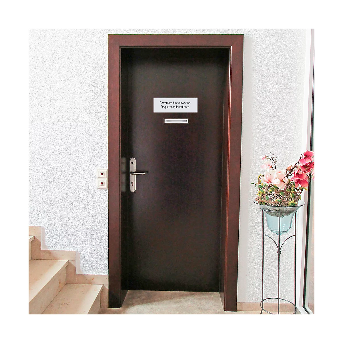 Porte en bois sombre avec panneau : "Formularsche unterlagen, Registration insert here". Fleurs à droite.
