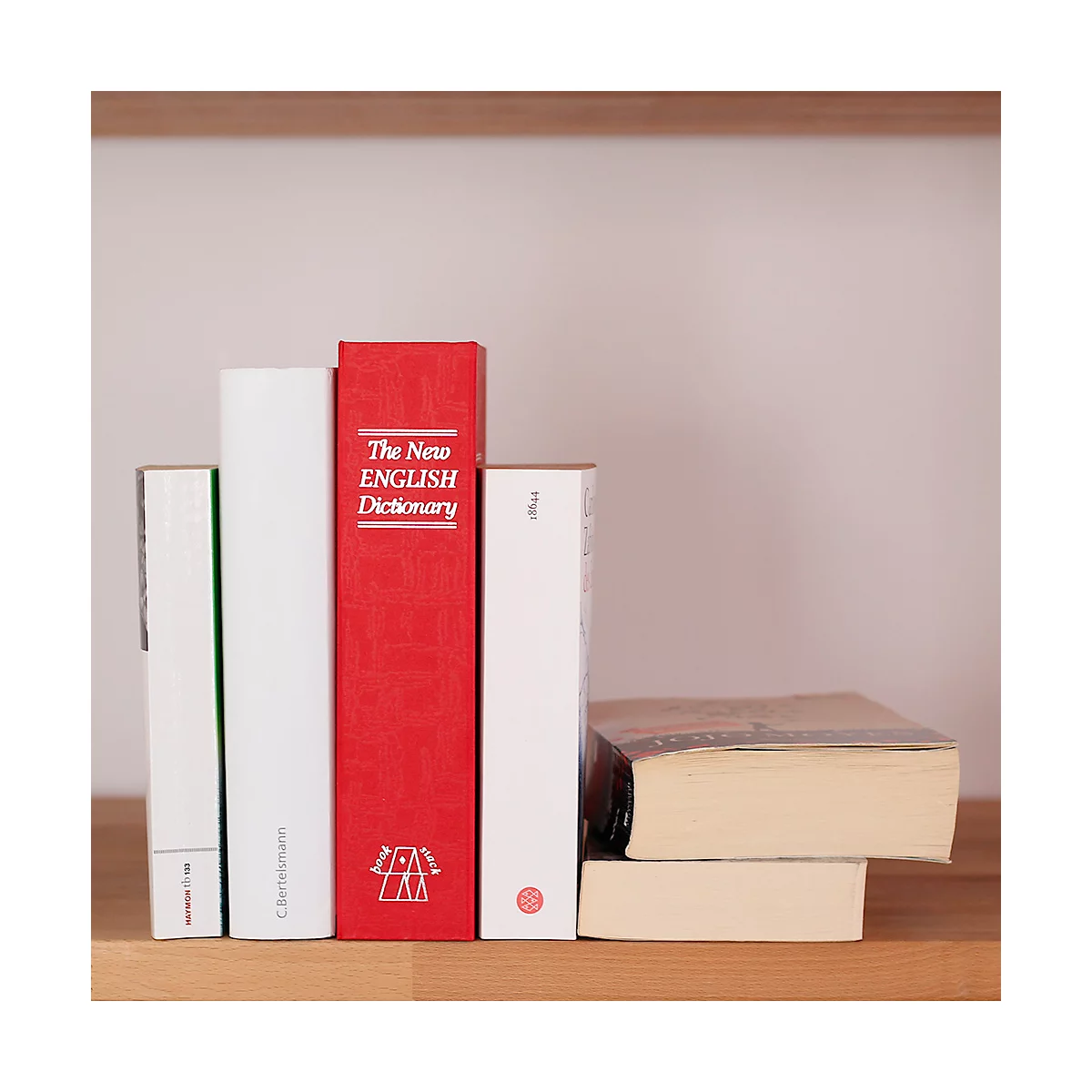 Plusieurs livres sont posés sur une étagère, dont un dictionnaire rouge avec des lettres blanches.