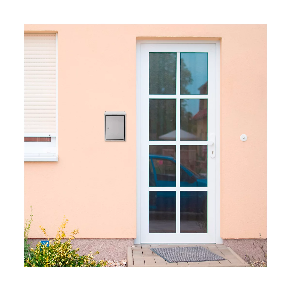 Helle Hausfassade mit weißer Tür, Fenster, Rollladen und Briefkasten. Im Fenster ein blaues Auto.