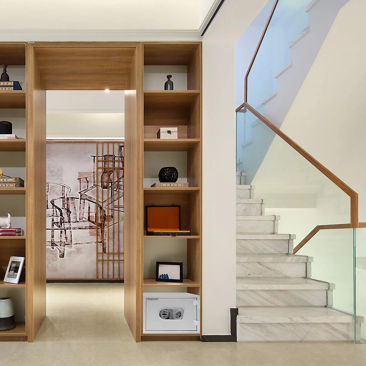 Ein weißer Tresor steht in einem Holzregal, dahinter eine Wendeltreppe mit Glasgeländer.