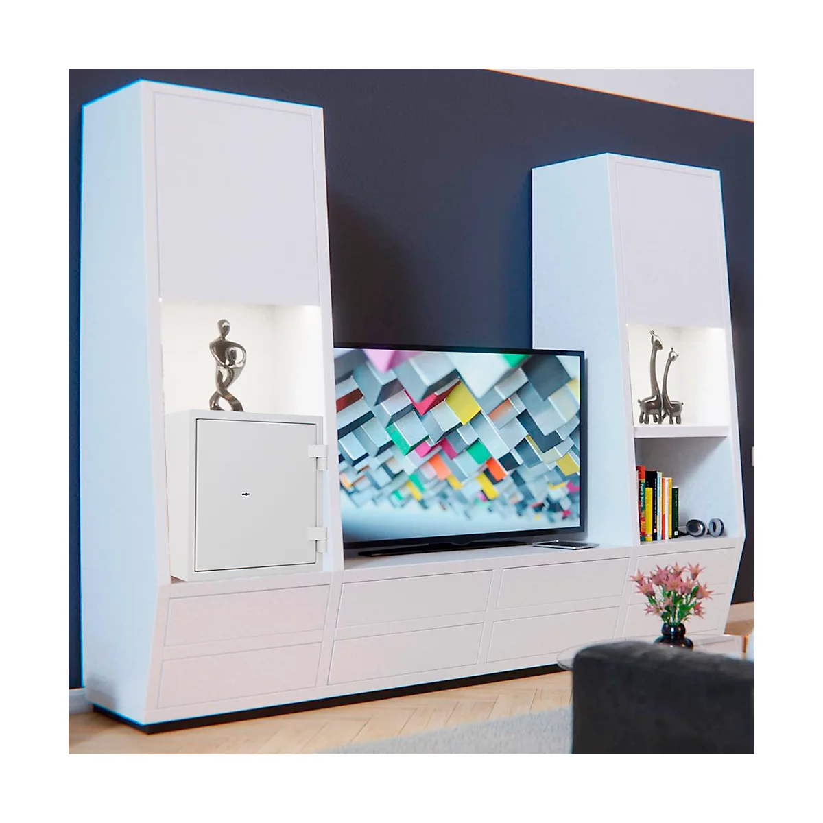 White living room wall unit with TV, art objects and safe. A dark wall in the background.