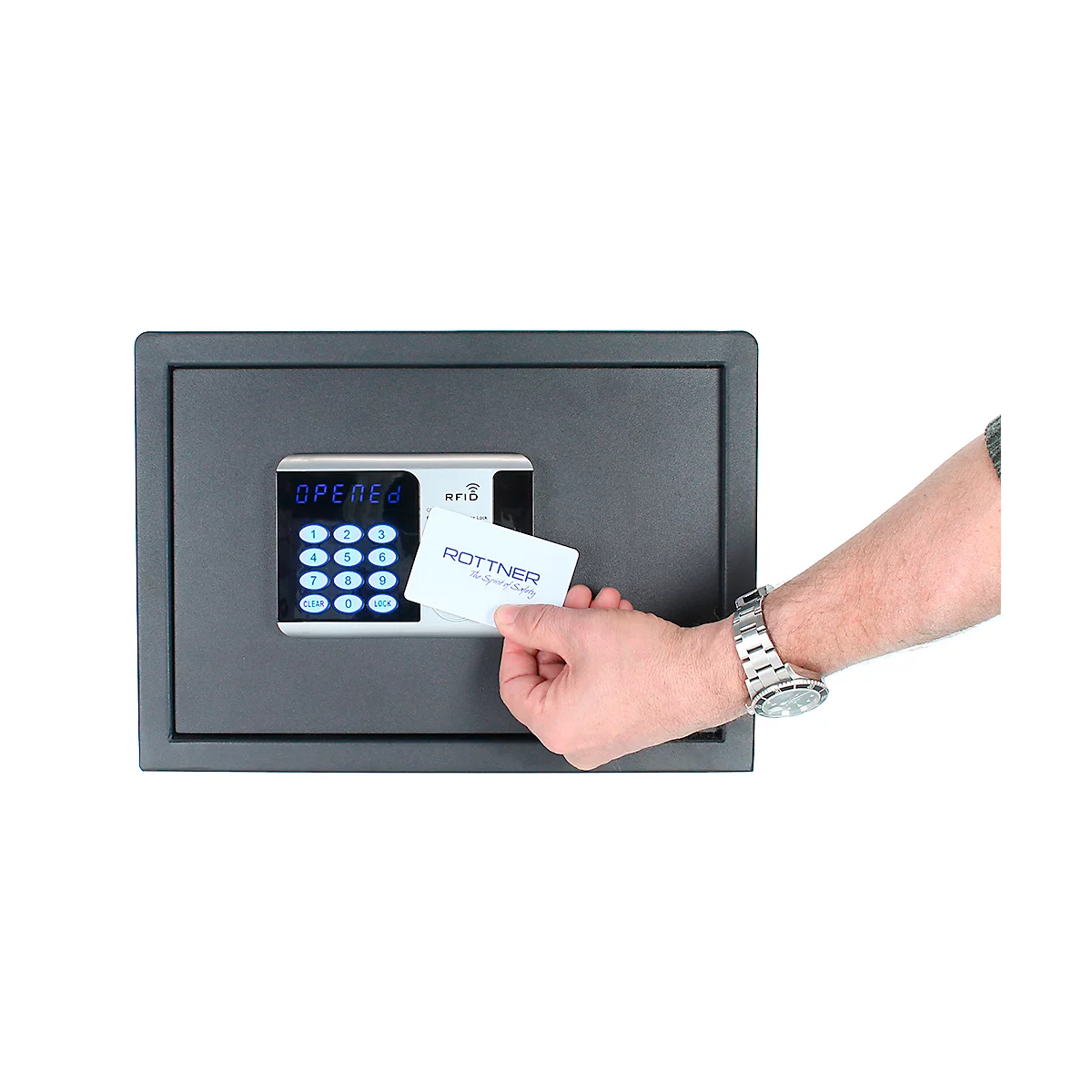 A man holds a card in front of a black safe lock. There are numbers on the display. The card says Rottner.