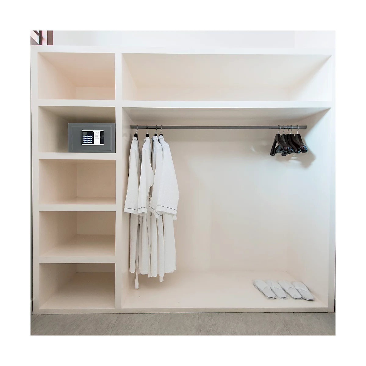 Beige built-in closet with bathrobes, hangers, safe, and slippers.