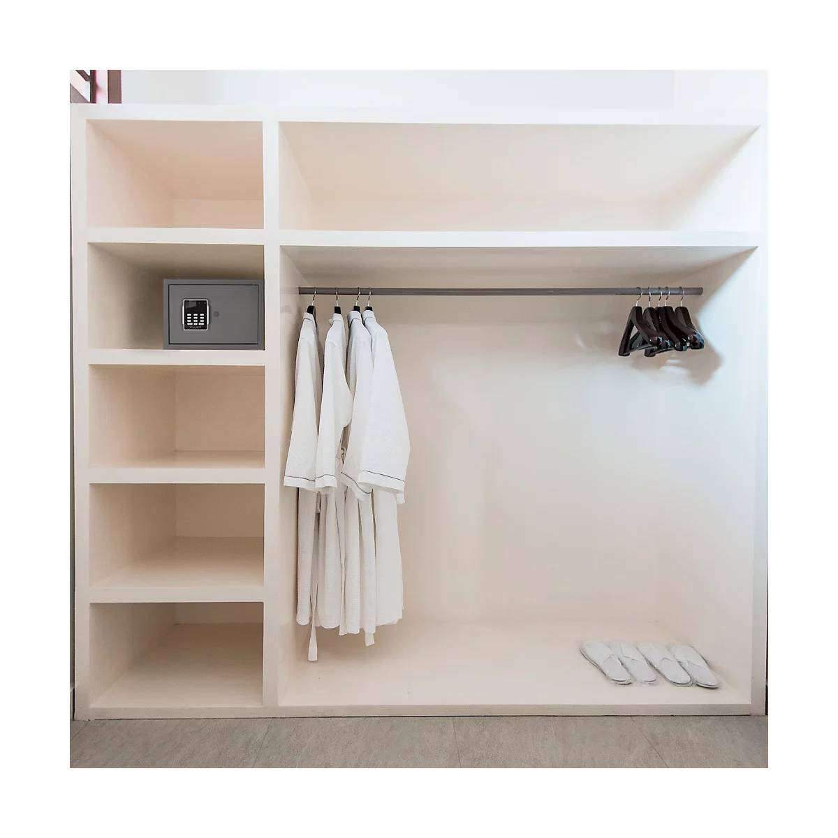 Beigefarbener Schrank mit integriertem Tresor, Bademänteln, Bügeln und Hausschuhen.