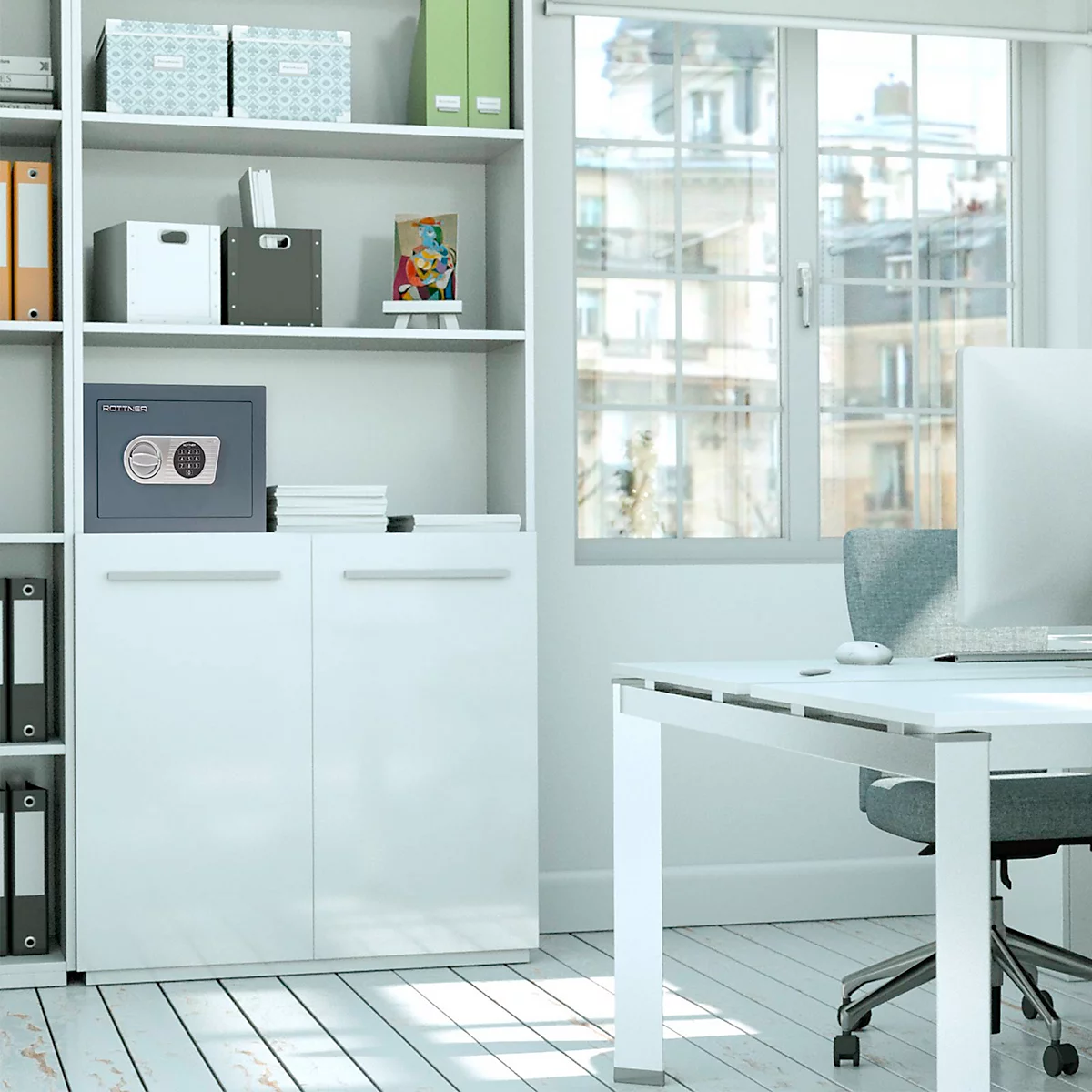 Bright office space with desk, bookcase, and safe. In the background view of buildings through a window.