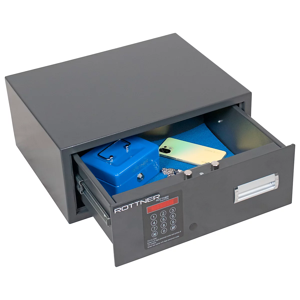 Grauer Tresor, Schublade geöffnet. Inhalt: Blaue Geldkassette, Smartphone, Schlüssel und Dokumente.