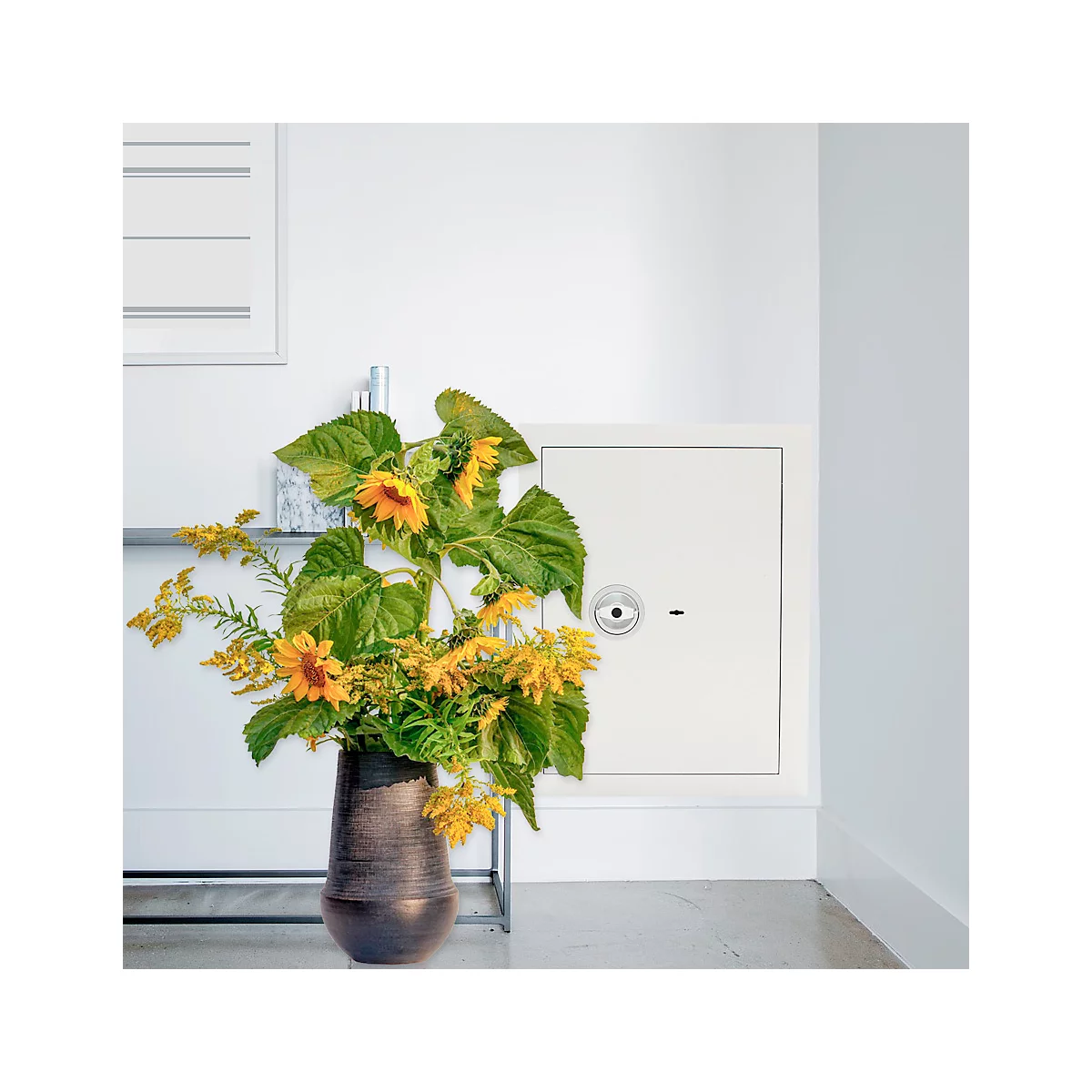 Eine Vase mit Sonnenblumen und gelben Blüten steht vor einem weißen Schrank.