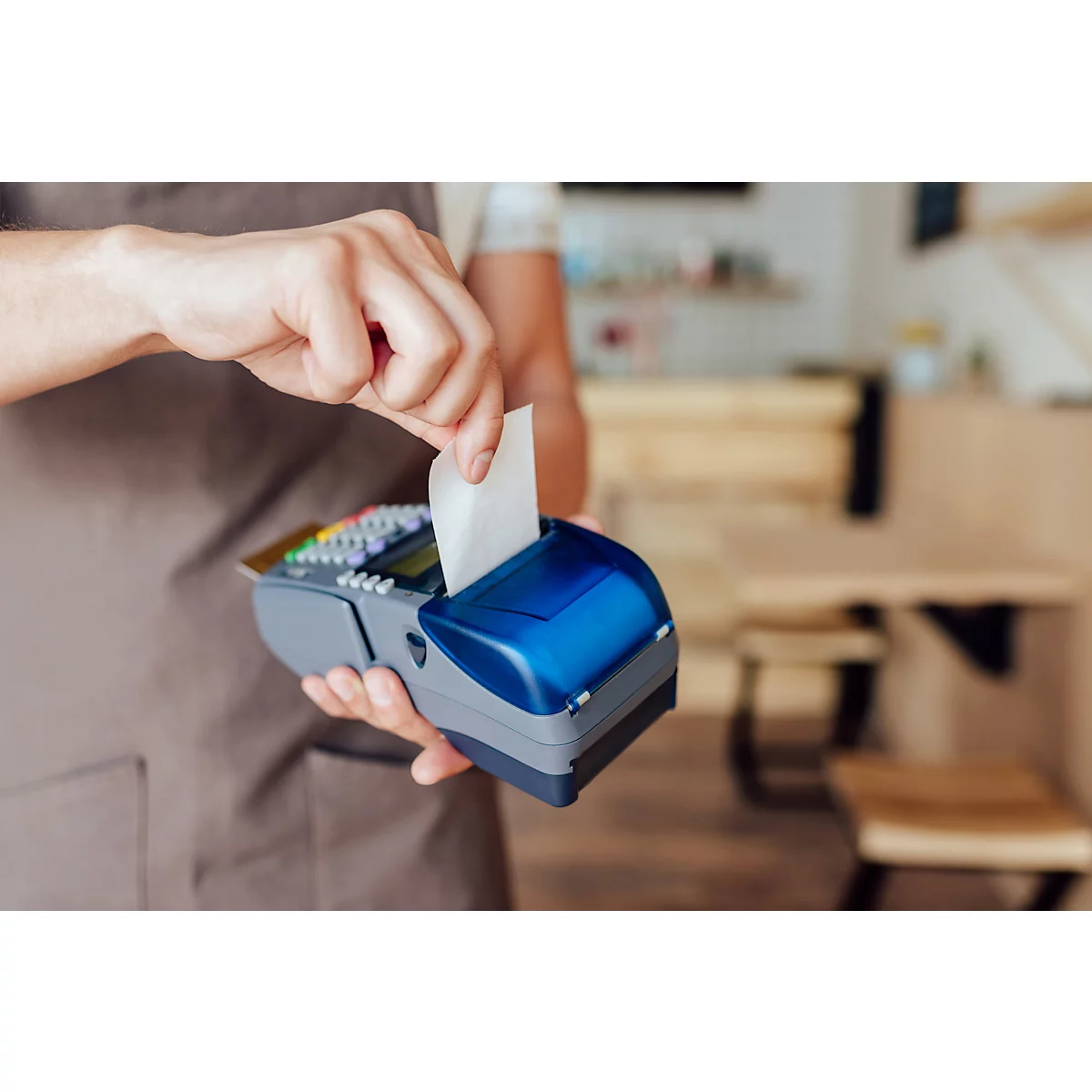 Un employé prend un reçu d'un appareil de paiement par carte bleu et gris.