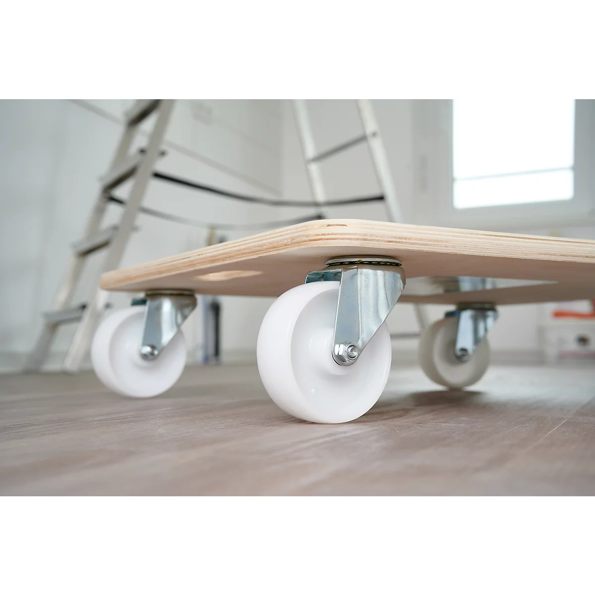 Un chariot en bois avec quatre roues blanches, une échelle en arrière-plan.