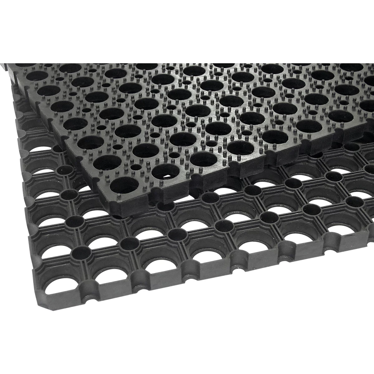 Detailopname van een zwarte rubberen mat met gaten en kleine spikes voor antislip eigenschappen. Een andere mat ligt erboven.
