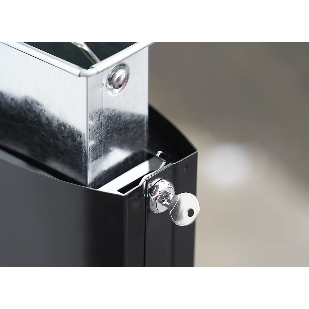 Nahaufnahme einer schwarzen Metallstruktur mit einer silberfarbenen Metallbox und einem kleinen Schlüsselloch mit Schlüssel.