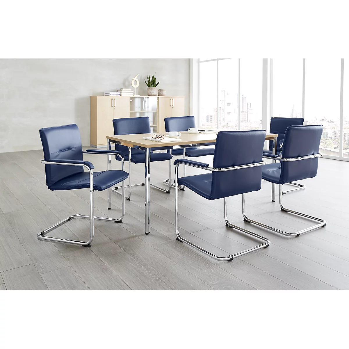 Conference room with table, six chairs with blue upholstery and a large window.