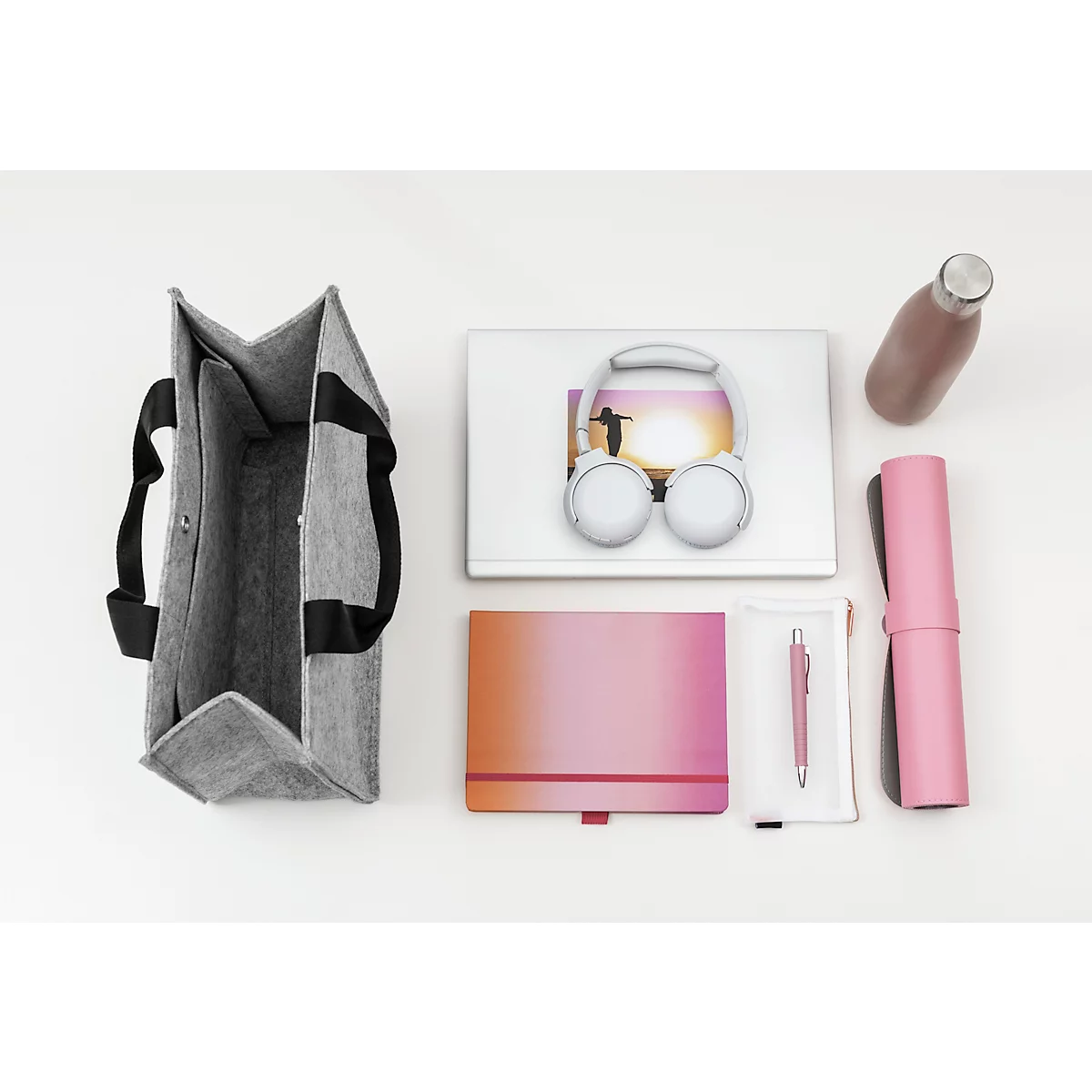 Sac en feutre gris avec contenu : ordinateur portable, casque, carnet, stylo, bouteille d'eau, tapis de yoga.