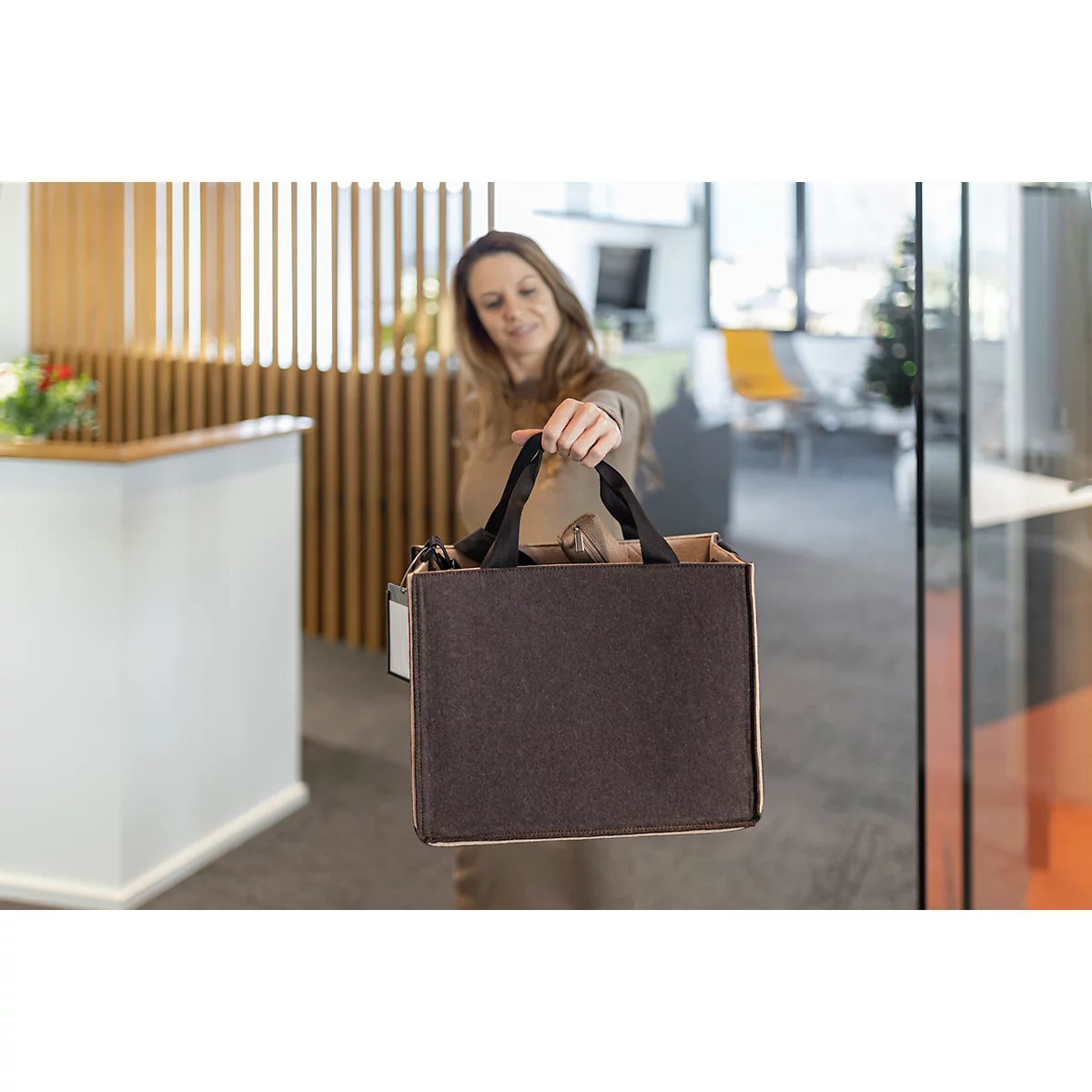 Une femme tient un panier marron, l'appareil photo est concentré sur le panier.