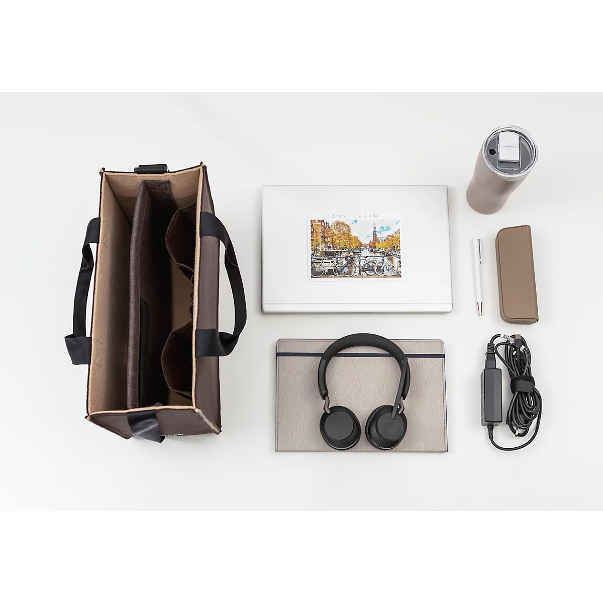 Sac à main marron avec ordinateur portable, casque, tasse, stylo, étui de téléphone et chargeur, sur fond blanc.