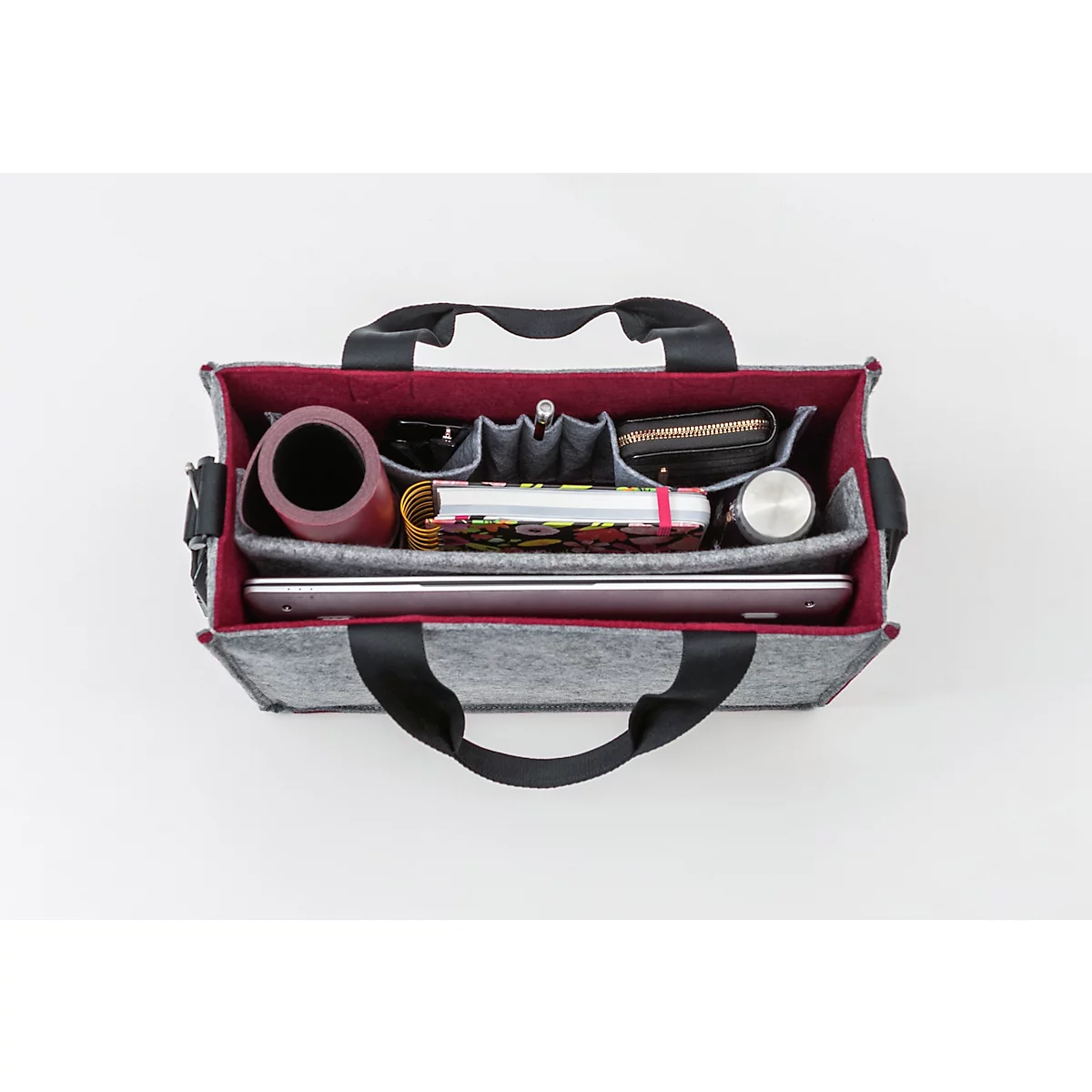 Sac à main en feutre gris avec des sangles de transport noires. Intérieur rouge rempli d'objets tels qu'un ordinateur portable, une bouteille d'eau et un carnet.