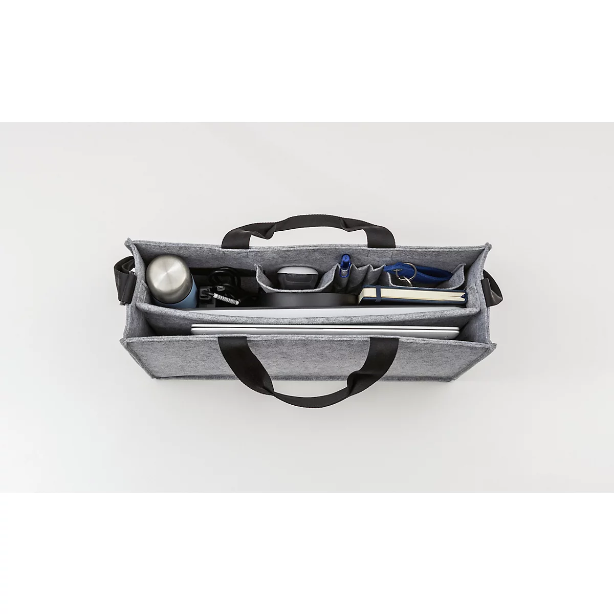 Sac en feutre gris avec contenu : thermos, ordinateur portable, stylos, bloc-notes et clés. Poignées noires.