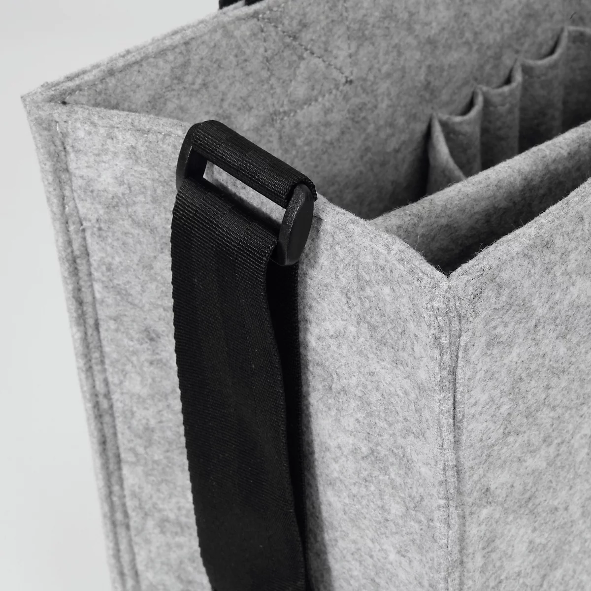 Sac en feutre gris avec une bandoulière noire fixée au bord du sac. À l'intérieur, plusieurs compartiments.
