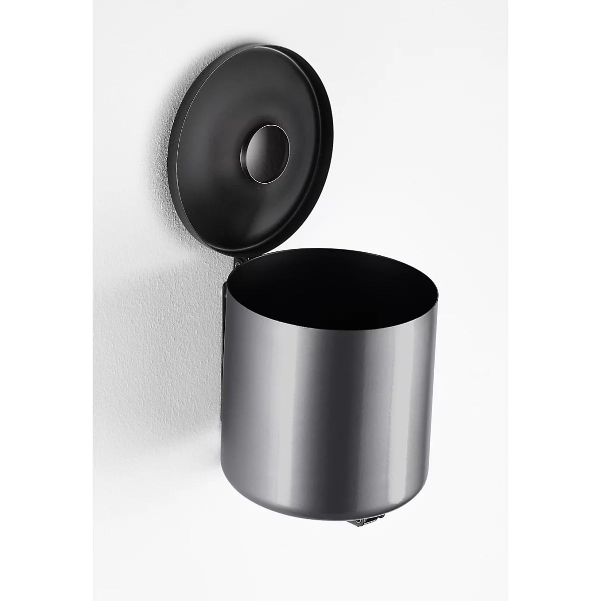Round, black wall-mounted trash can with an open lid. The can is fixed to a white wall.