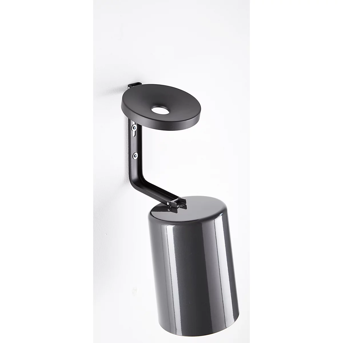 A metal wall mount, with a cylindrical container and a round shelf, attached to the wall.