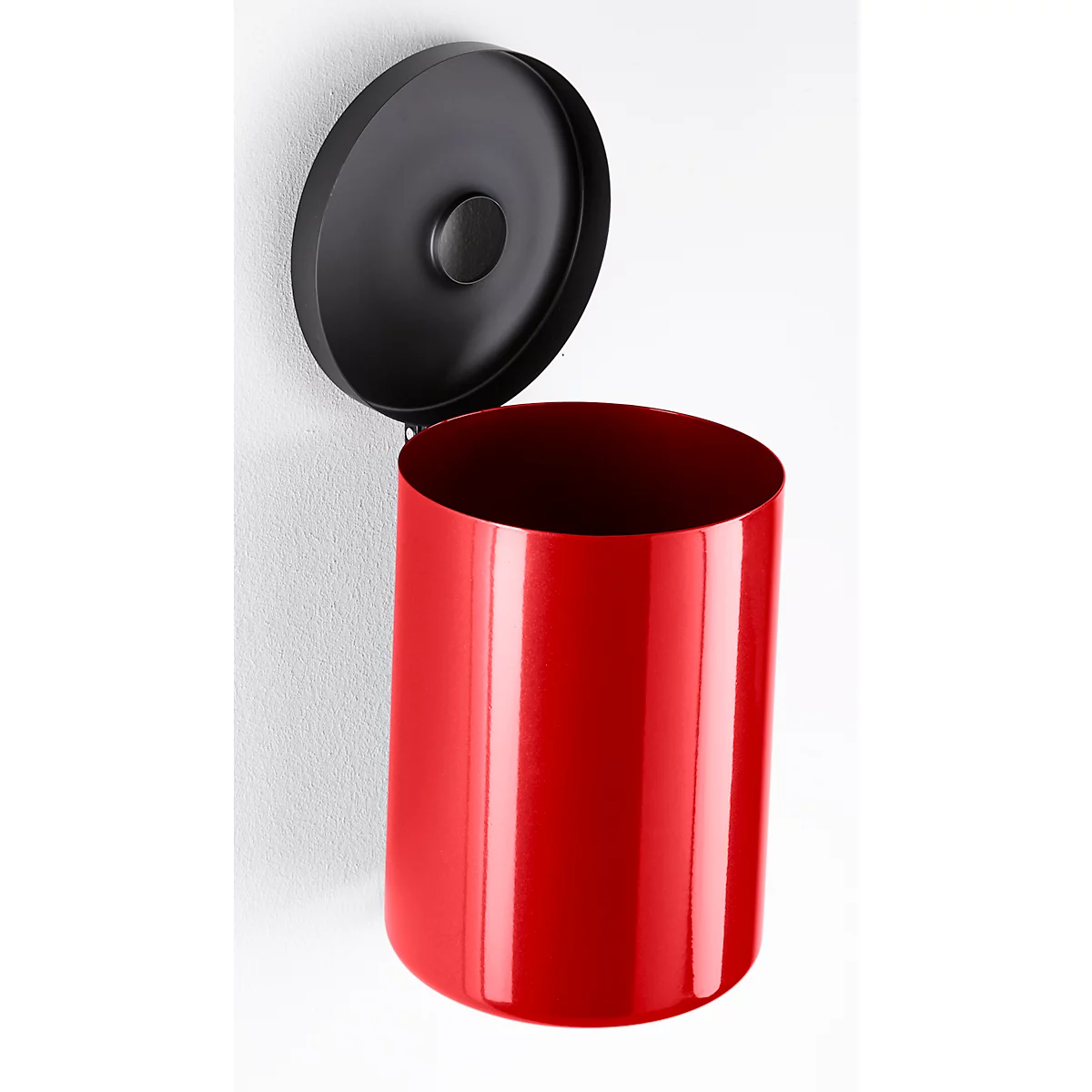 Red trash can with open black lid on white wall. Cylindrical shape shines.
