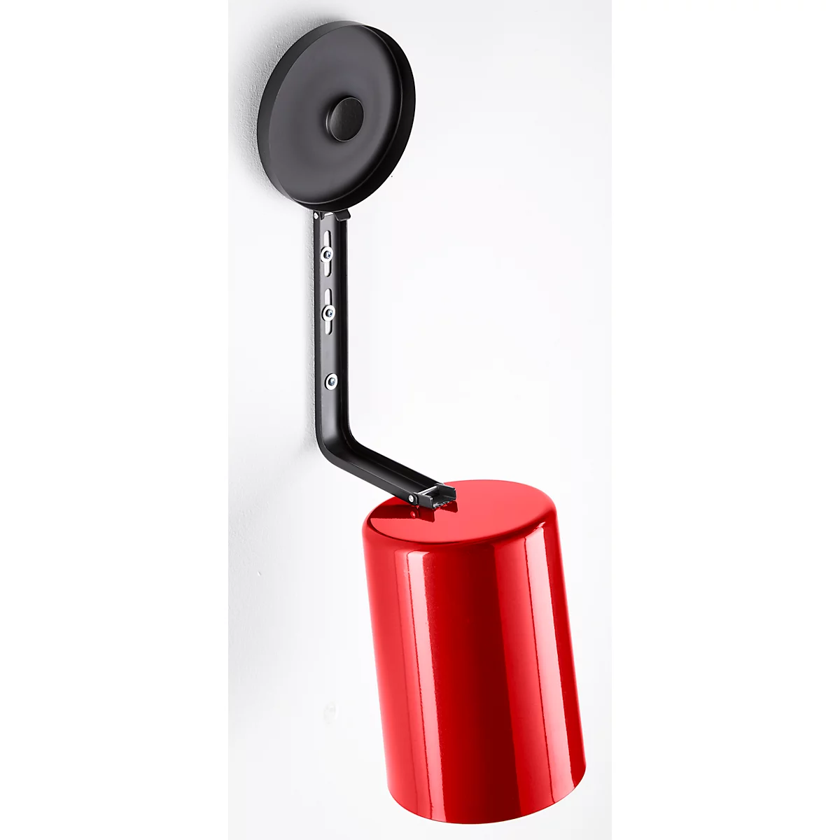 A wall lamp consisting of a red cylinder and a black, round shade, on a black arm.