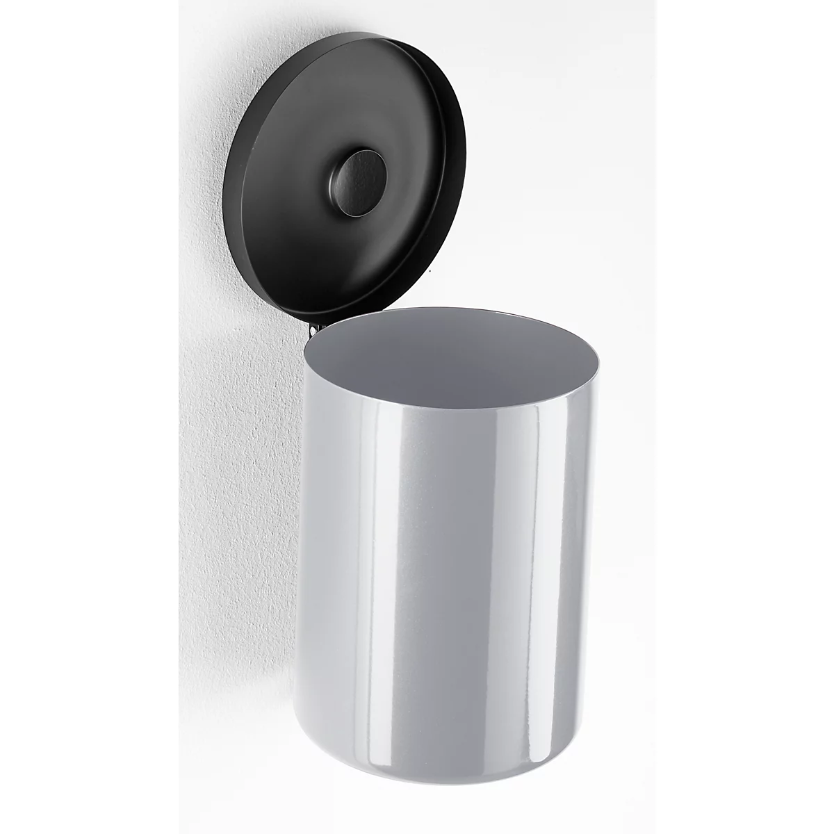 Gray cylindrical trash can with open black lid on a white wall.