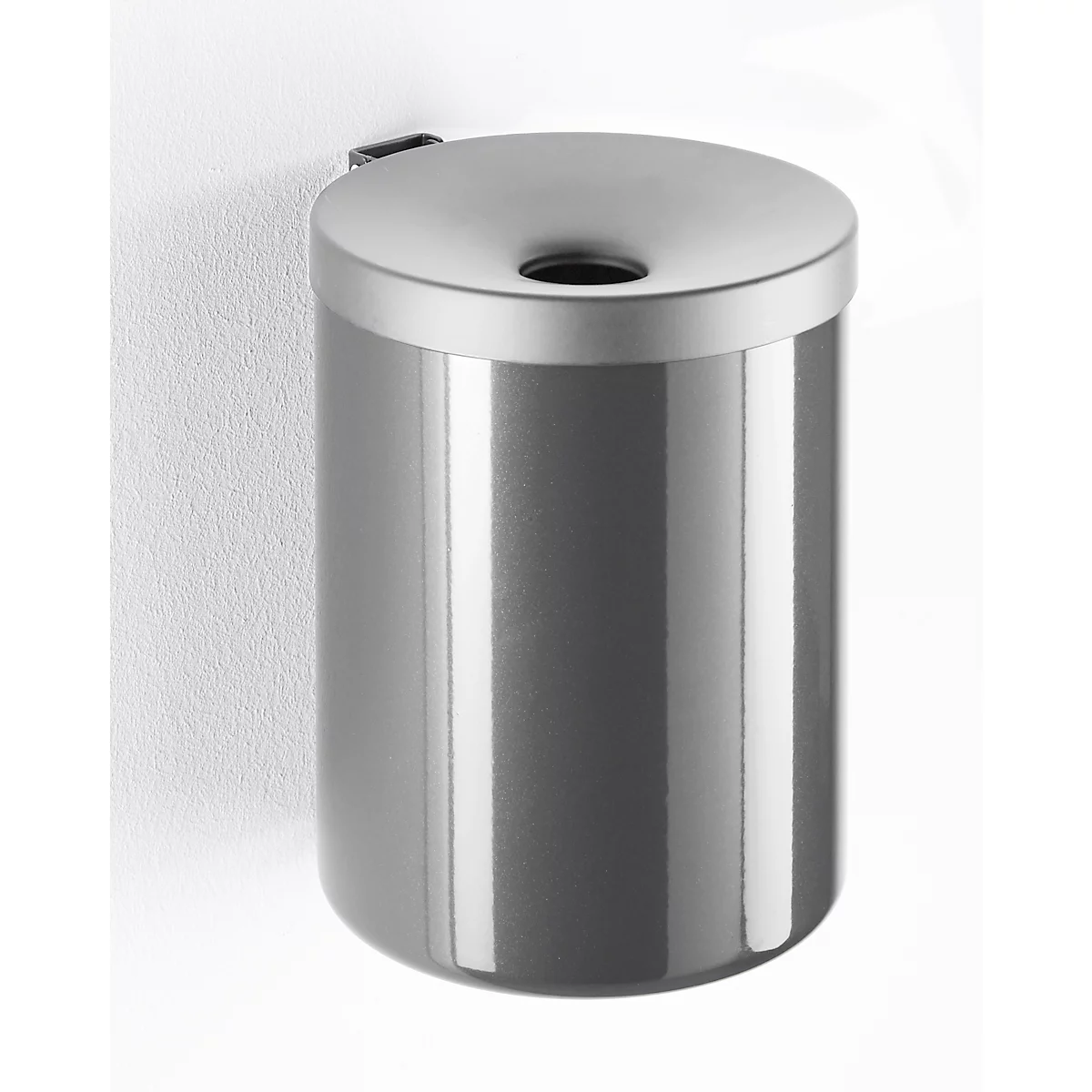 Gray, cylindrical wall-mounted waste bin with lid. Top with hole for trash. Mounted on white wall.