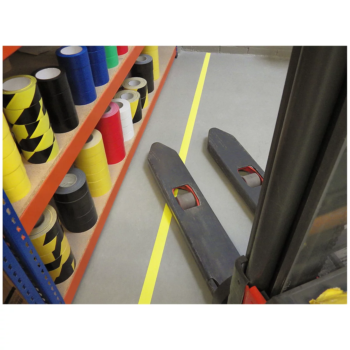A forklift and shelves with colored adhesive tapes, yellow line on the floor.